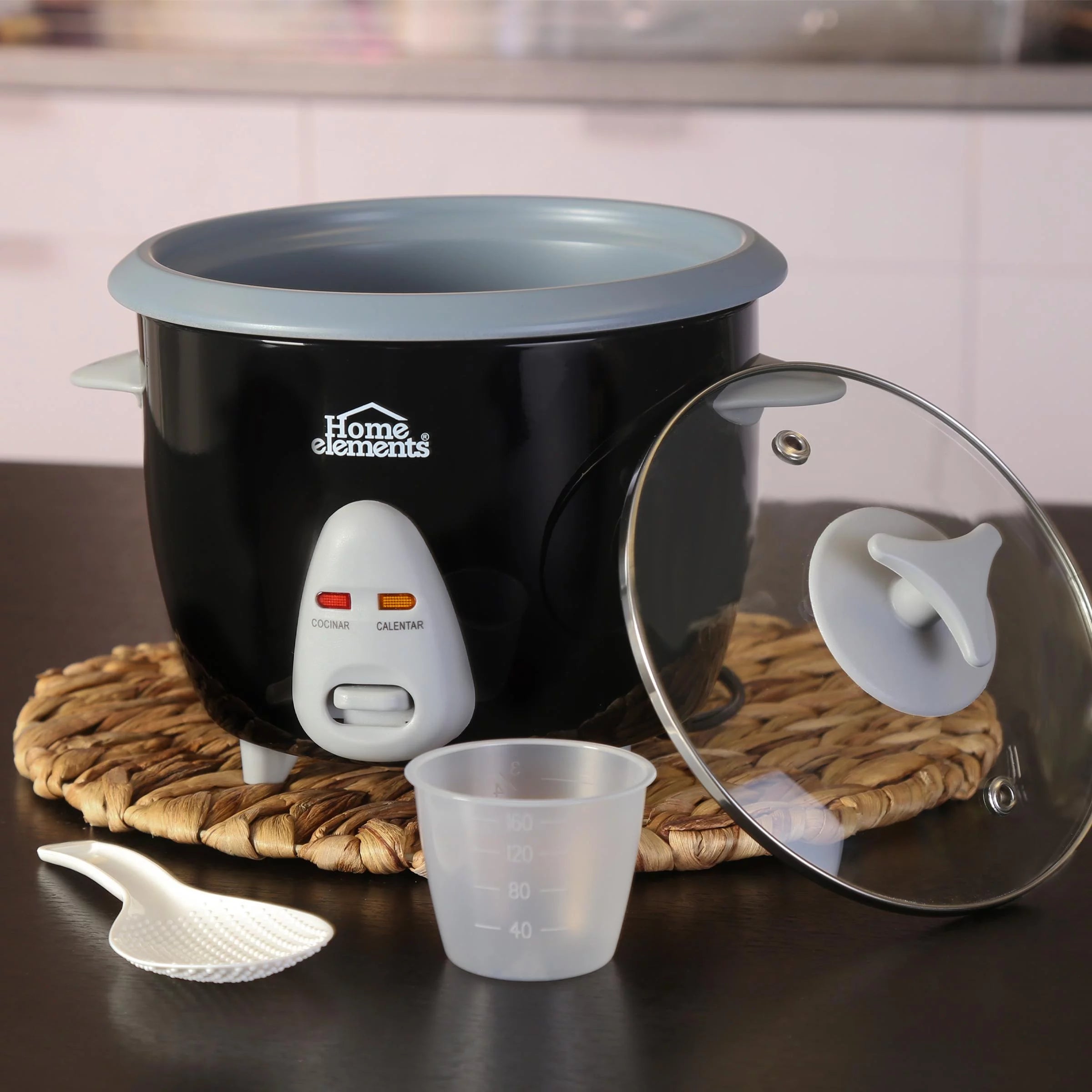 Olla Arrocera Home Elements de 1 litro en color negro con tapa de vidrio, recipiente antiadherente, cuchara plástica y taza medidora.