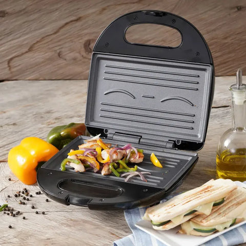 Sanduchera Universal Grill con diseño de sonrisa, placas antiadherentes, cubierta de baquelita y indicadores luminosos.