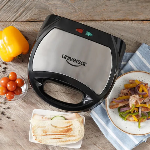 Sanduchera Universal Grill con diseño de sonrisa, placas antiadherentes, cubierta de baquelita y indicadores luminosos.